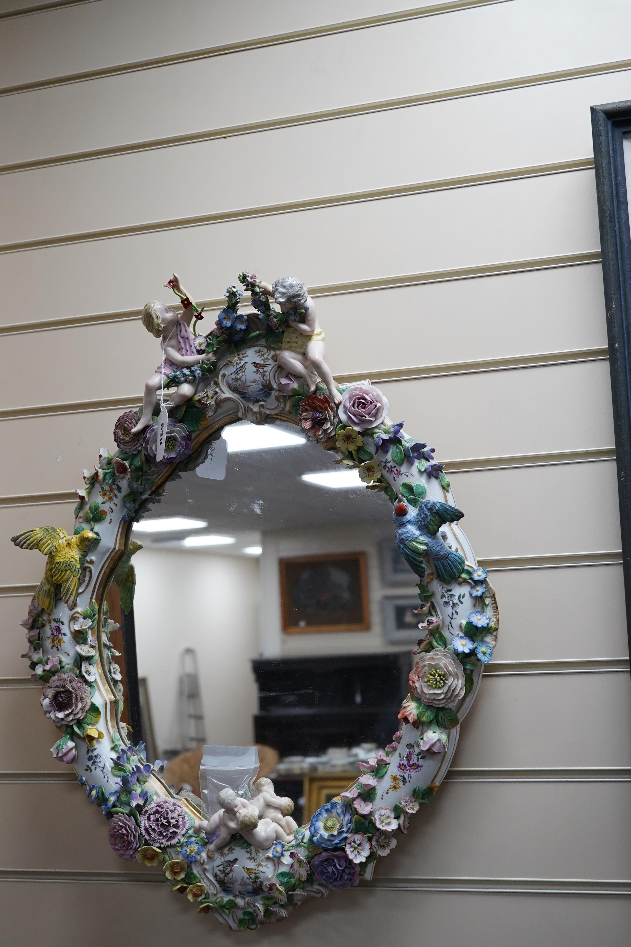 A Meissen style porcelain floral encrusted and figural mirror, 64cm high. Condition - fair, minor losses